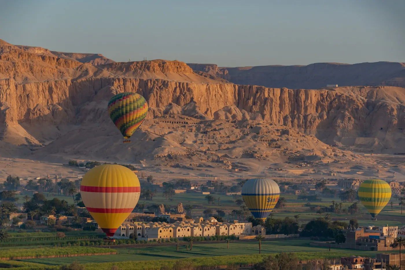 Hot-air balloons at sunrise over Luxor's West Bank, with the Theban hills behind