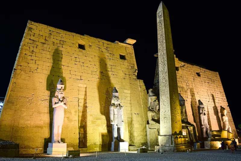 The pylon, statues and obelisk of Luxor Temple lit up at night